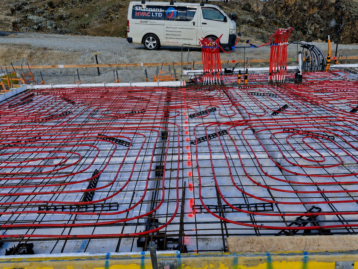 Underfloor heating loops tied out across a slab before the pour, with a Shannons HVAC van on site